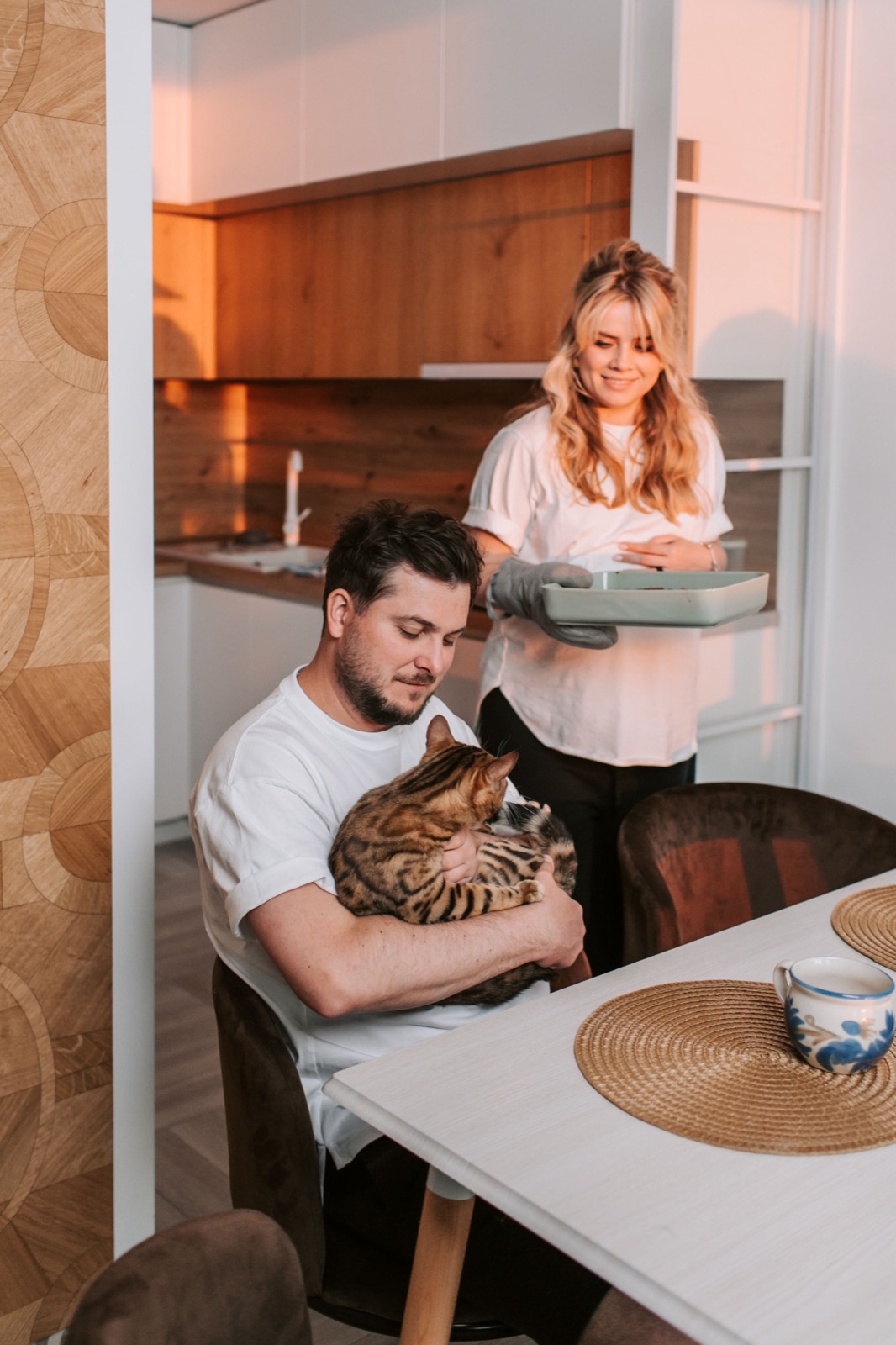Man and woman in a kitchen with a Bengal cat