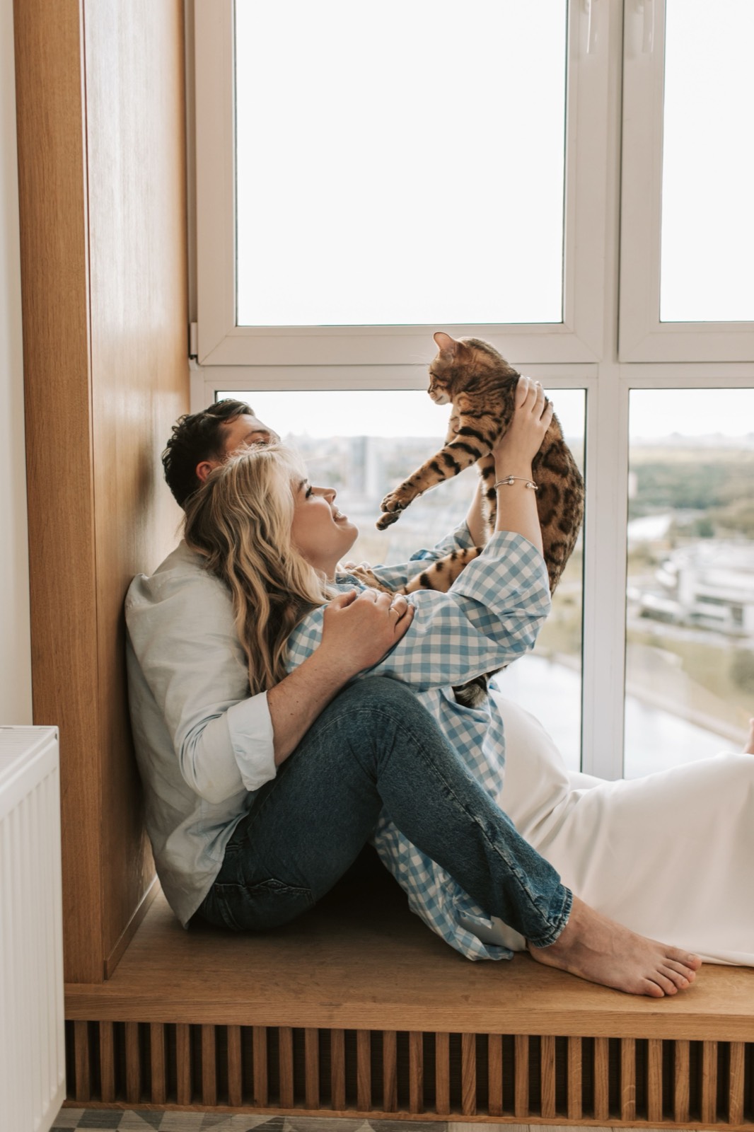 Couple on a window ledge with a Bengal cat