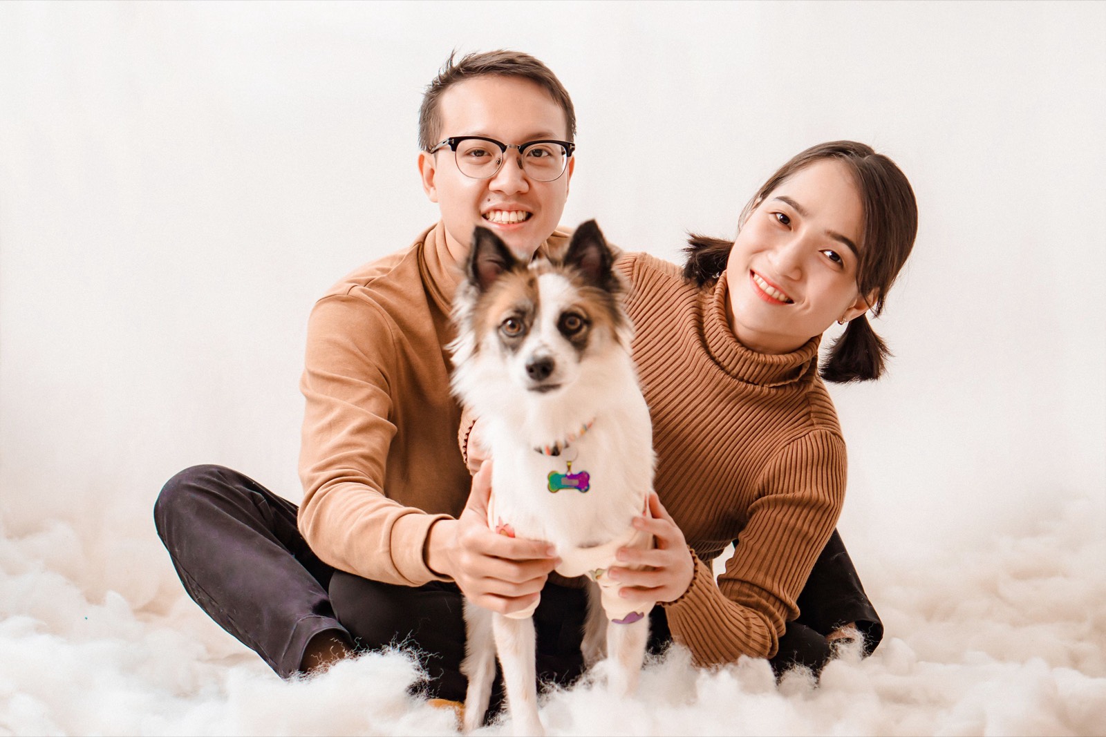 Couple holding a small white and brown dog