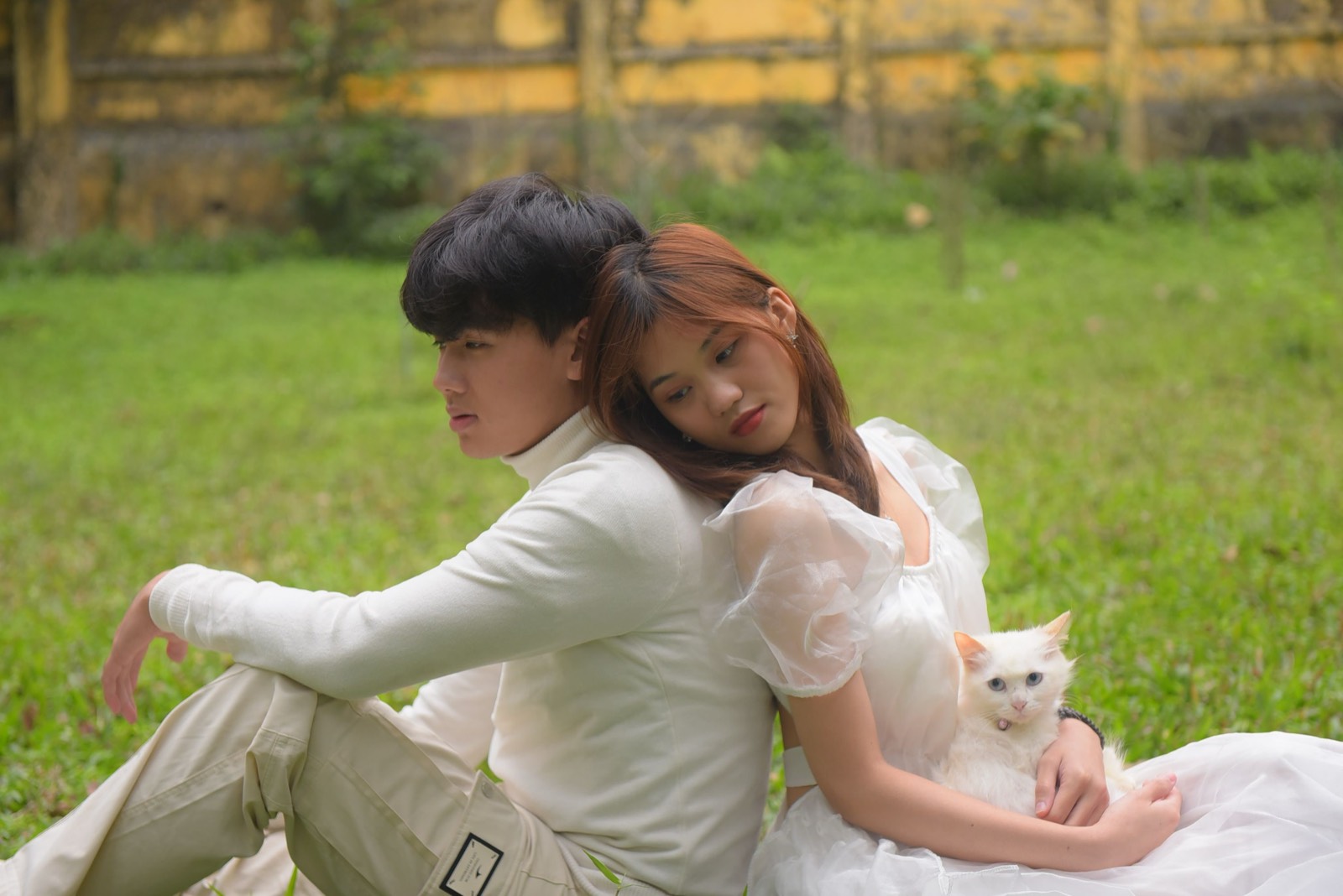 Couple on a lawn with a fluffy white cat